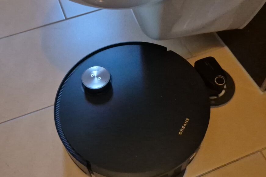 Der Wischarm des Dreame X60 Pro Ultra fährt seitlich unter ein Möbelstück aus